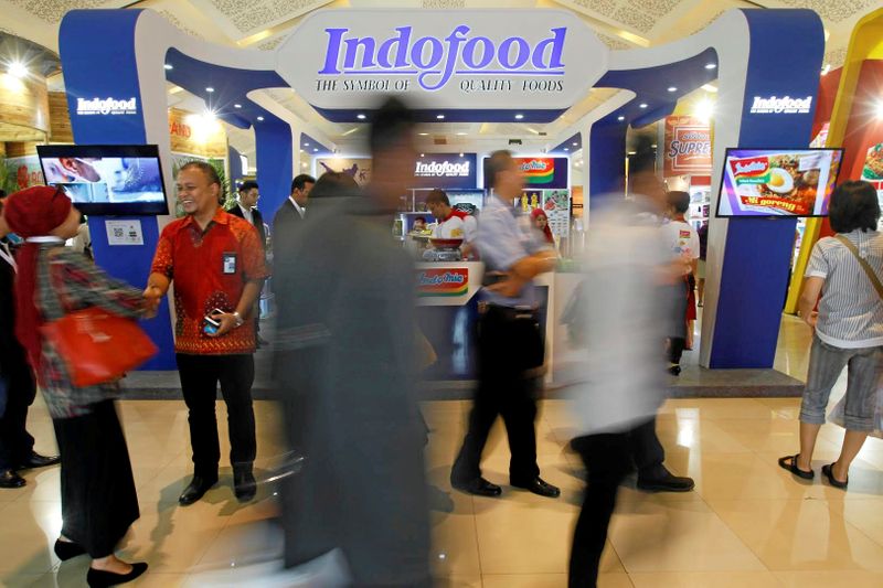 &copy; Reuters. FILE PHOTO: Visitors walk past the booth of Indonesian food giant Pt. Indofood Sukses Makmur at a trade exhibition in Jakarta,