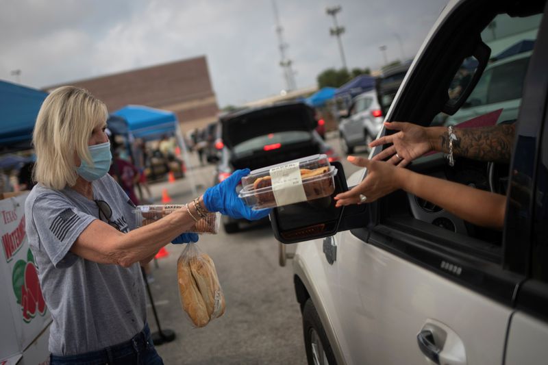 &copy; Reuters. Volunteer give food to residents economically affected by COVID 19 pandemic during San Antonio Food Bank distribution in Texas