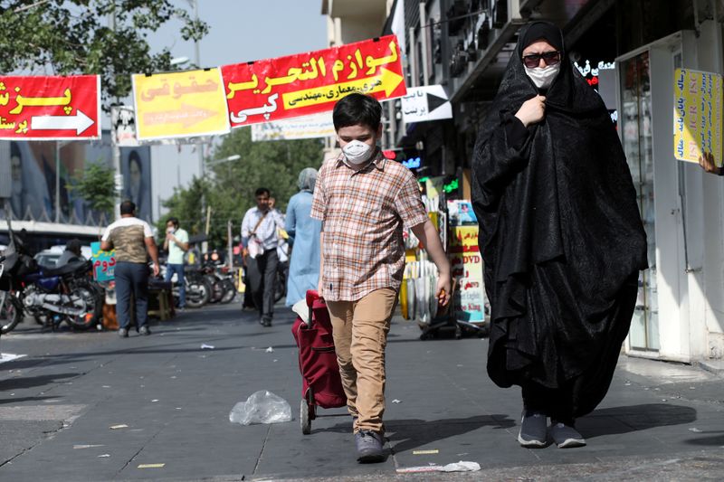 &copy; Reuters. FILE PHOTO: An Iranian woman and her son wearing a protective face mask walks the street, following the outbreak of the coronavirus disease (COVID-19), in Tehran