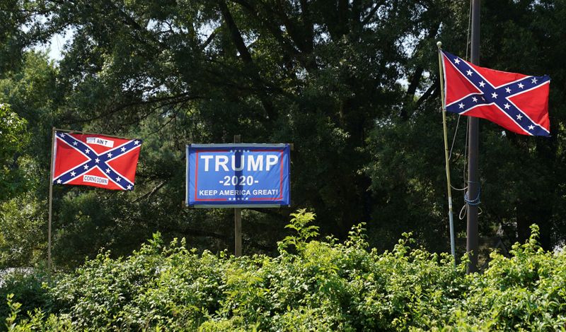 &copy; Reuters. Un cartel de la campaña del presidente de los Estados Unidos, Donald Trump, entre dos banderas confederadas, en Sandston, Virginia, EEUU
