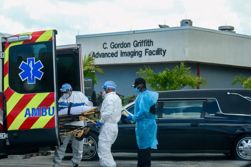 &copy; Reuters. Equipos médicos llegan con un paciente mientras un auto funerario sale con un cadáver del North Shore Medical Center de Miami, Florida, EEUU.