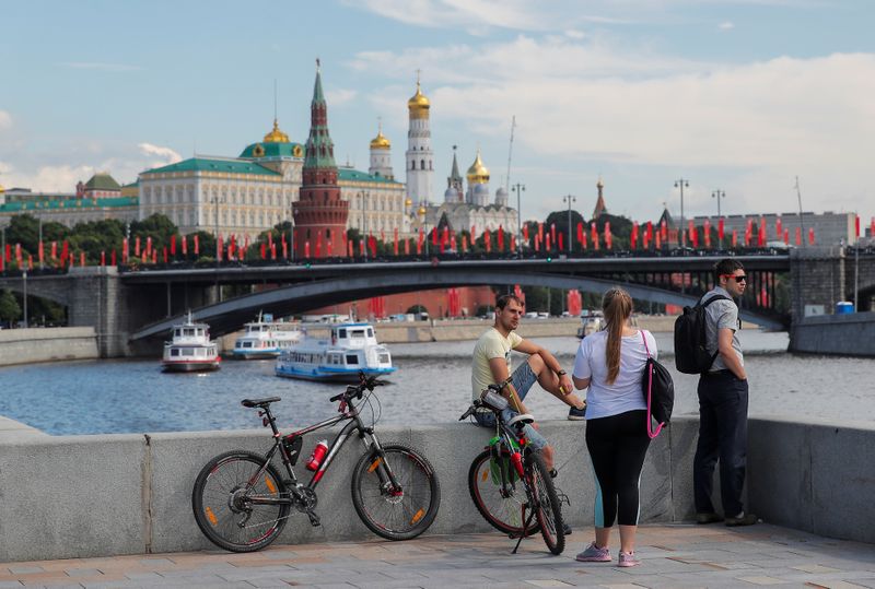 &copy; Reuters. FILE PHOTO: People rest on an embankment as cruise vessels sail near the Kremlin in Moscow