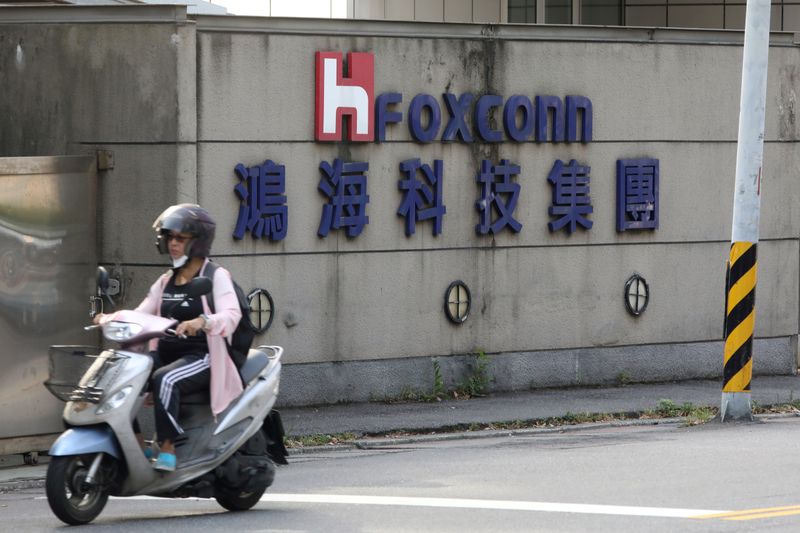 &copy; Reuters. FILE PHOTO: A person riding a scooter wears a mask amid the outbreak of the coronavirus disease (COVID-19), while passing a Foxconn office building in Taipei