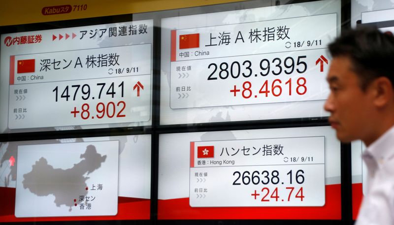 © Reuters. Homem passa por painem mostrando índices acionparios da China em corretora de Tóquio