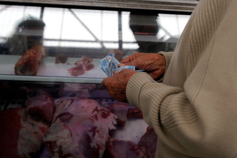 © Reuters. Man counts money to pay meat products at Granada market in Mexico City