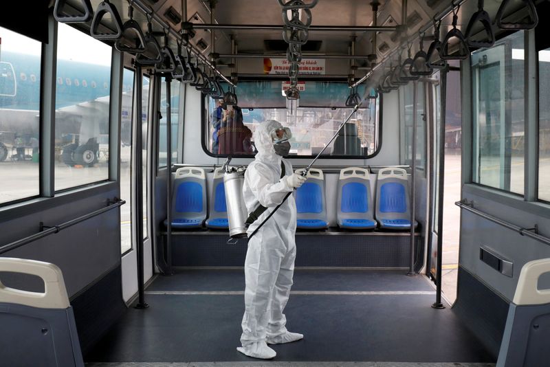 © Reuters. FILE PHOTO: A health worker sprays disinfectant inside a bus to protect from the recent coronavirus outbreak, at Noi Bai airport in Hanoi, Vietnam