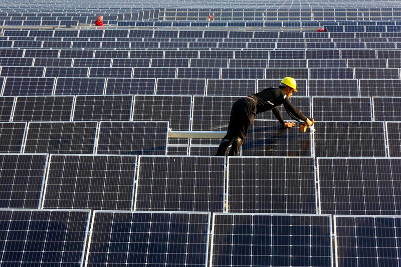 © Reuters. Man works on solar panels at a solar power plant of China Huaneng Group in Huaiyin