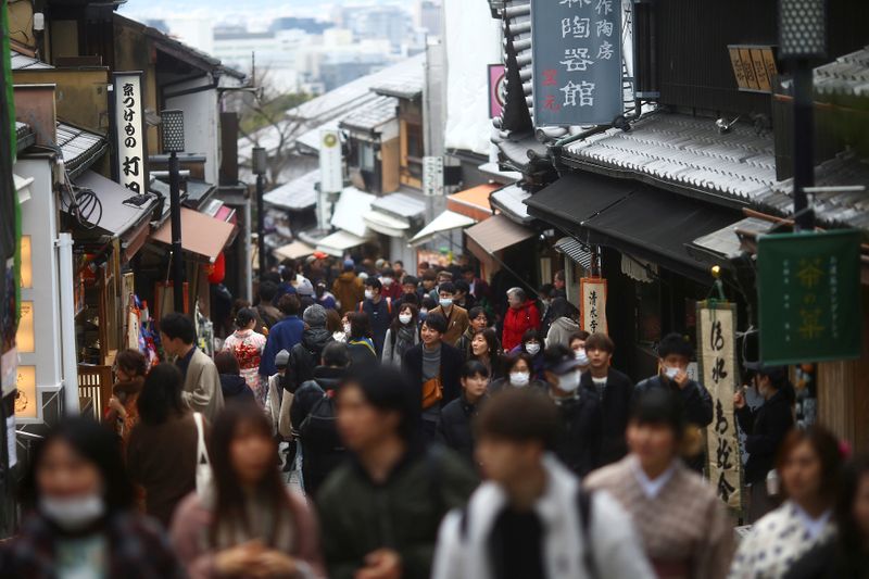 &copy; Reuters. FILE PHOTO: People, wearing protective masks following an outbreak of the coronavirus disease (COVID-19), walk on a street of Gion district in Kyoto