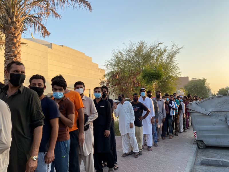 &copy; Reuters. Unemployed men queue for food handouts from concerned local residents after they lost incomes due to the coronavirus disease (COVID-19) pandemic in Dubai