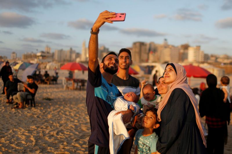 &copy; Reuters. A Palestinian man takes a selfie with his family on a beach after COVID-19 restrictions were eased, in Gaza City