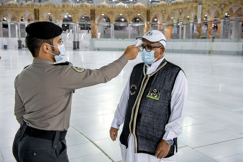 &copy; Reuters. A security man checks the temperature of a worker as they work on raising the Kiswa, a silk cloth covering the Holy Kaaba, before the annual pilgrimage season, at the Grand Mosque in Mecca