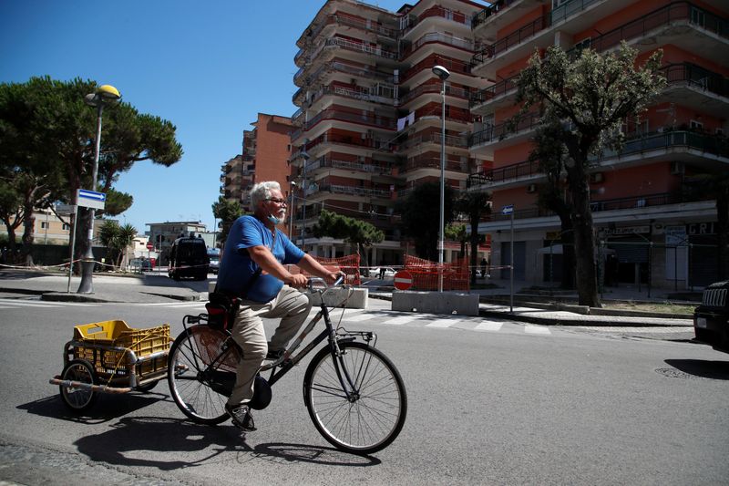 &copy; Reuters. A man rides his bicycle near a residential complex where more than 40 people tested positive for the coronavirus disease (COVID-19) in Mondragone