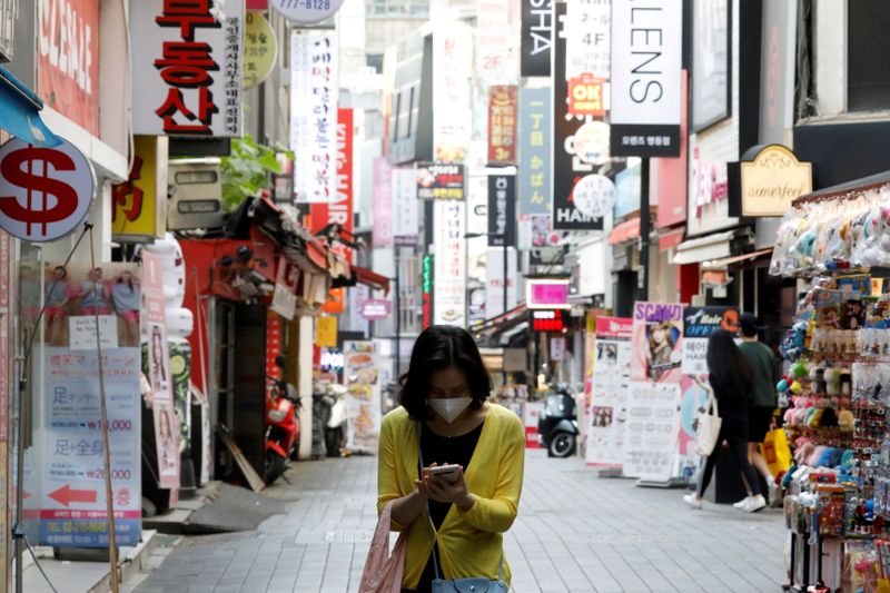 &copy; Reuters. FILE PHOTO: A woman wearing a mask looks at her mobile phone amid social distancing measures to avoid the spread of the coronavirus disease (COVID-19), in Myeongdong shopping district in Seoul