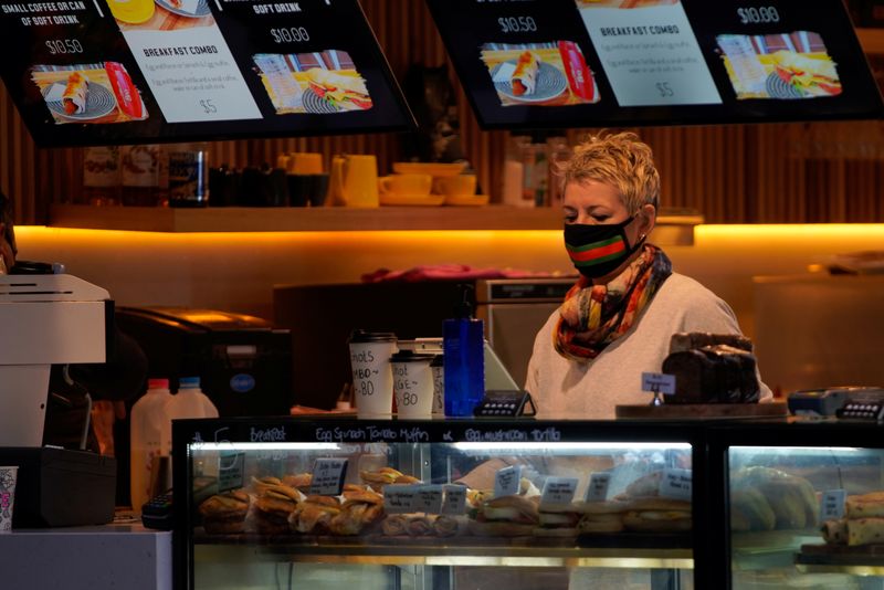 © Reuters. A worker wears a protective face mask in a cafe in Melbourne, the first city in Australia to enforce mask-wearing to curb a resurgence of COVID-19