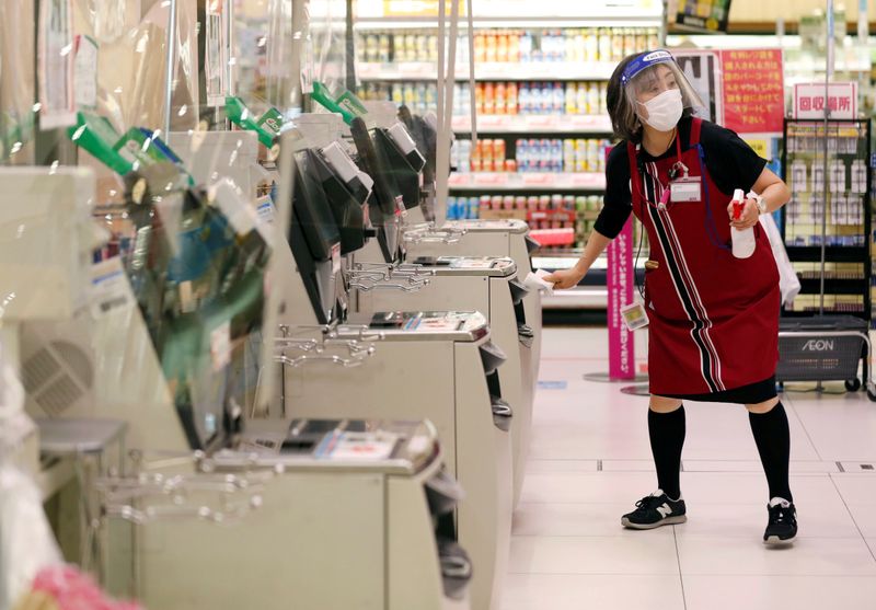 © Reuters. FILE PHOTO: A staff memeber cleans automated check out counters with alcohol at Japan's supermarket group Aeon's shopping mall as the mall reopens amid the coronavirus disease (COVID-19) outbreak in Chiba