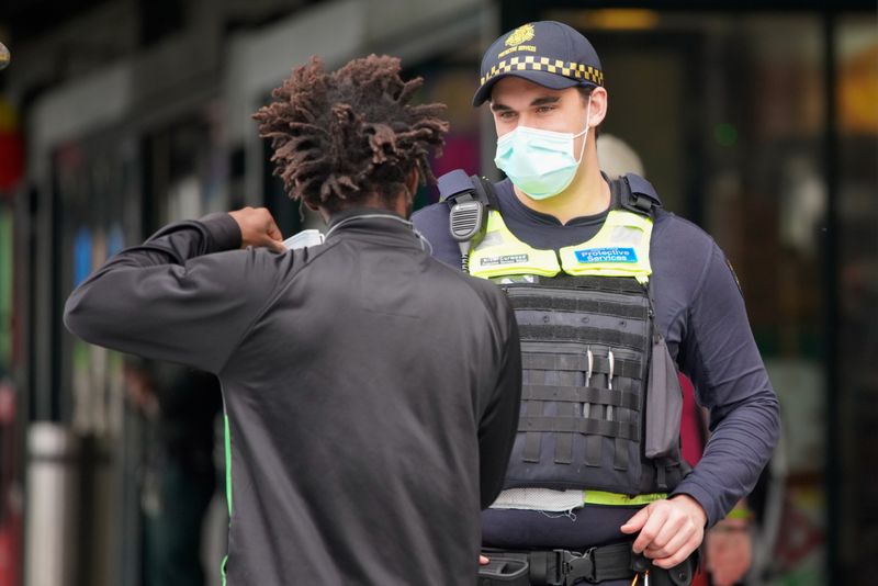 &copy; Reuters. A Protective Services Officer wearing a face mask talks to a member of public in Melbourne, the first city in Australia to enforce mask-wearing to curb a resurgence of COVID-19