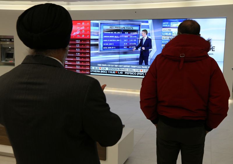 &copy; Reuters. Passersby watch the performance of stocks on a financial news television screen in the business district of Toronto