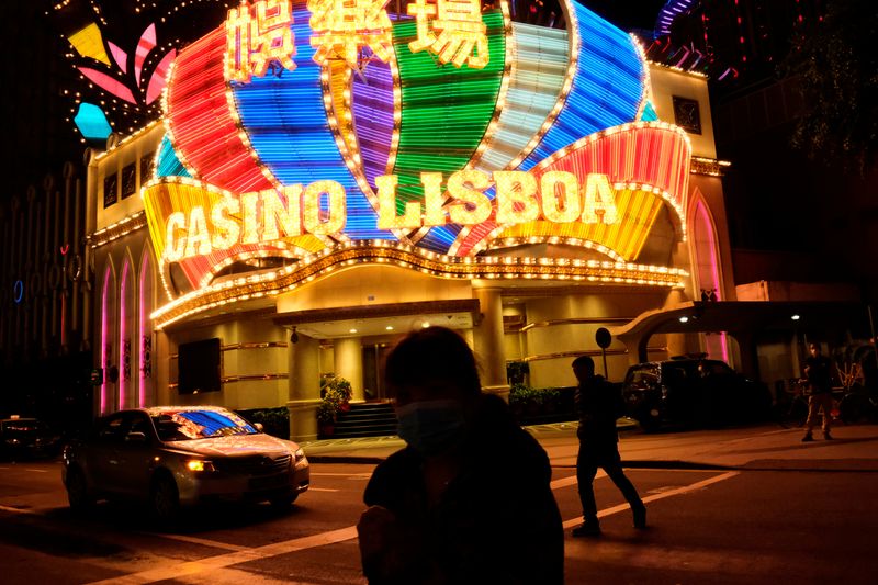 &copy; Reuters. FILE PHOTO: People wearing masks walk in front of Casino Lisboa in Macau