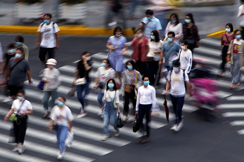 © Reuters. People wearing face masks walk on a street in Shanghai