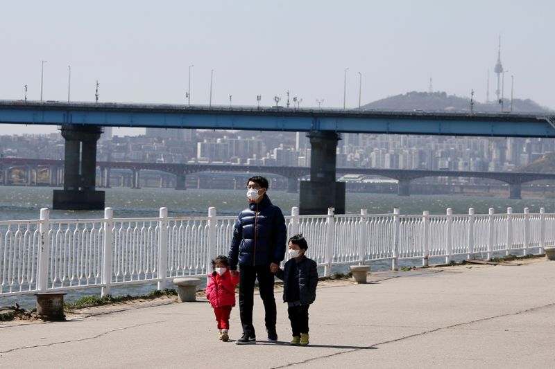 &copy; Reuters. FILE PHOTO: A man and children wearing masks to protect against contracting the coronavirus disease (COVID-19) take a walk at a Han River Park in Seoul