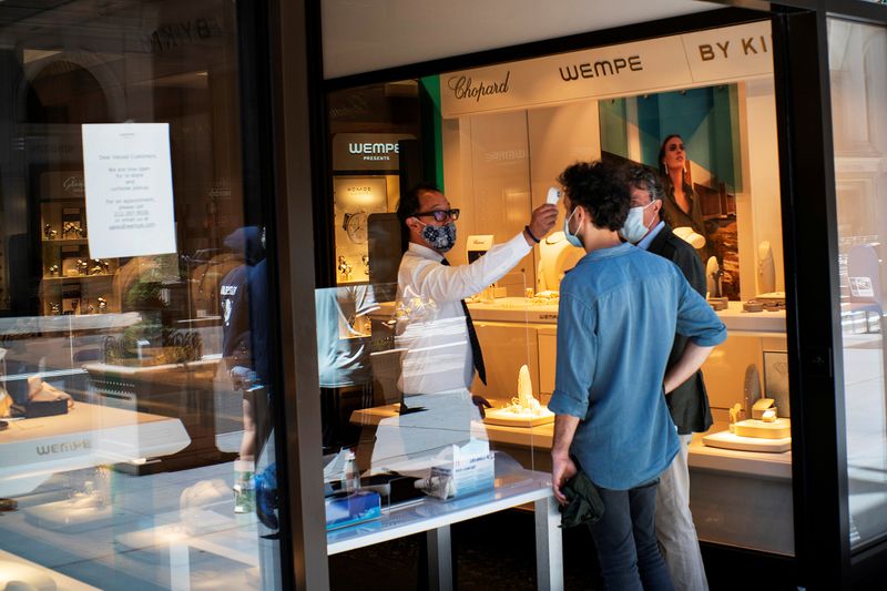 &copy; Reuters. FILE PHOTO: A worker checks the temperature of a client at local store opened for pick up, as phase one of reopening after lockdown begins, during the outbreak of the coronavirus disease (COVID-19), at 5th Avenue, in New York City