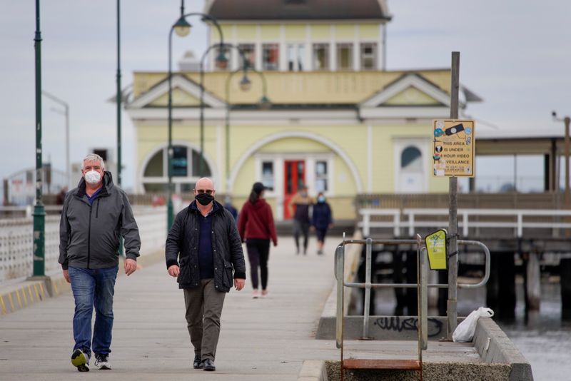 &copy; Reuters. Walkers wear protective face masks at St Kilda pier in Melbourne, the first city in Australia to enforce mask-wearing to curb a resurgence of COVID-19