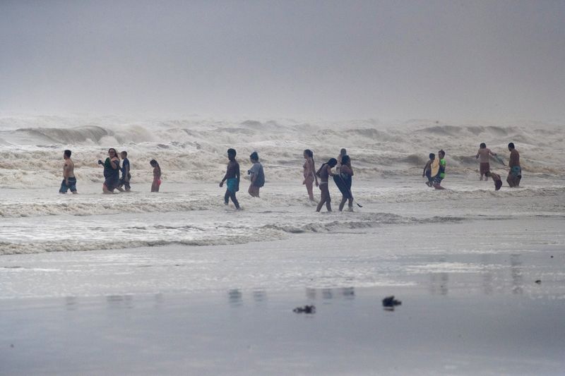 © Reuters. Beach-goers play in high swells from Hurricane Hanna in Galveston, Texas