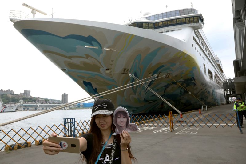 © Reuters. A woman takes a selfie in front of the Explorer Dream cruise ship, in Keelung