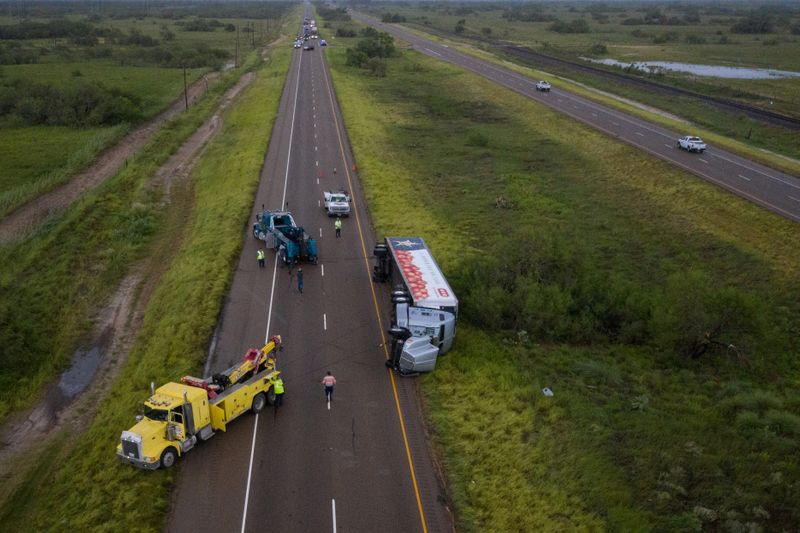 © Reuters. El tráfico está detenido mientras una grúa intenta levantar un camión volcado en la Ruta 77 por los fuertes vientos del huracán Hanna en Sarita