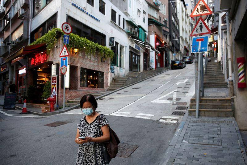 © Reuters. A woman wears a surgical mask while walking at Central following the coronavirus disease (COVID-19) outbreak in Hong Kong,