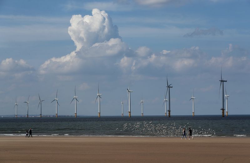 &copy; Reuters. FILE PHOTO: Wind turbines are seen as people stroll along Redcar beach, Britain