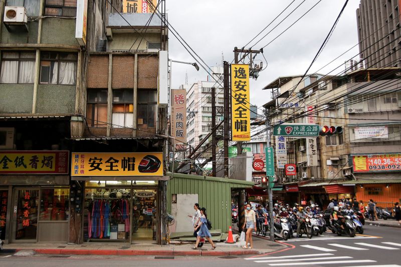 &copy; Reuters. People wearing face masks to protect themselves from the coronavirus disease (COVID-19) walk by shops in Taipei