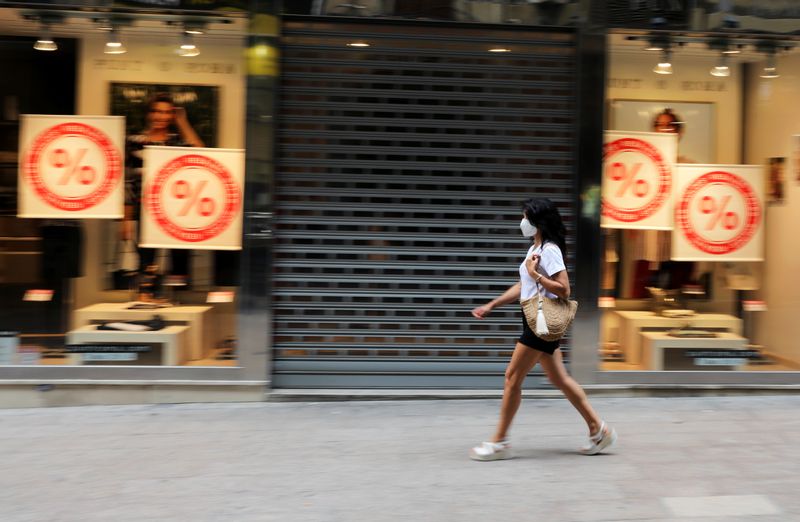 &copy; Reuters. FOTO DE ARCHIVO: Una mujer con mascarilla camina frente a una tienda cerrada en Lleida
