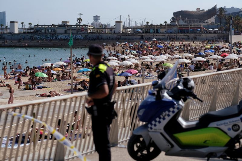 &copy; Reuters. Foto de archivo de un policía mirando al público que disfruta de un día de playa en Barcelona