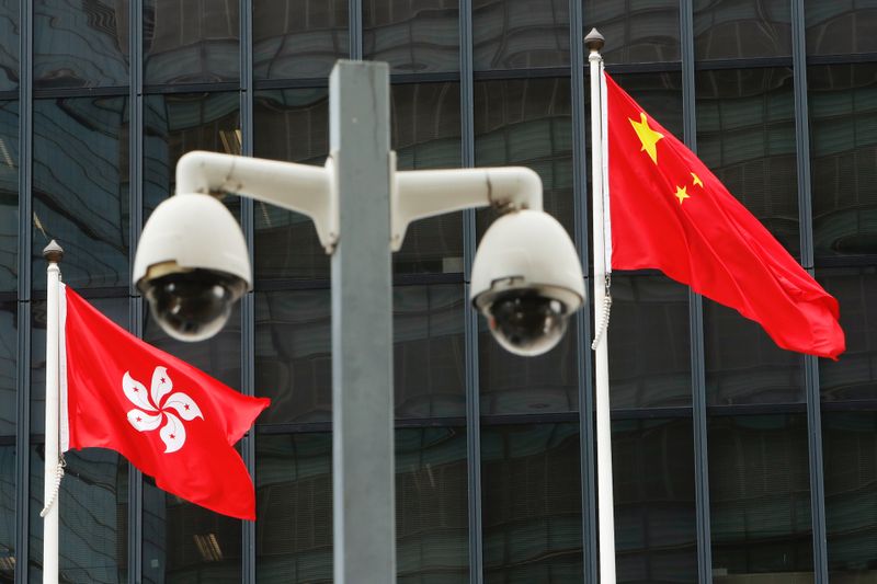 &copy; Reuters. FOTO DE ARCHIVO: Las banderas nacionales de Hong Kong y China ondean detrás de un par de cámaras de vigilancia en el exterior de las oficinas del gobierno central en Hong Kong, China