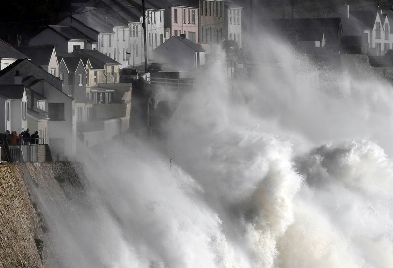 © Reuters. FILE PHOTO: Large waves crash along sea defences and the harbour as storm Ophelia approaches Porthleven in Cornwall, south west Britain