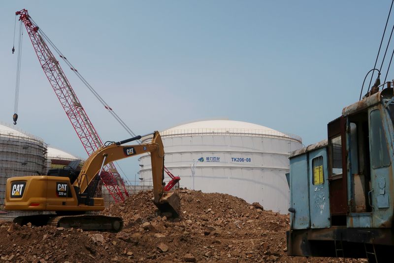 © Reuters. FILE PHOTO: A crude oil tank is seen behind a construction site at Hengli Petrochemical's new refining, petrochemical complex at Changxing island in Dalian