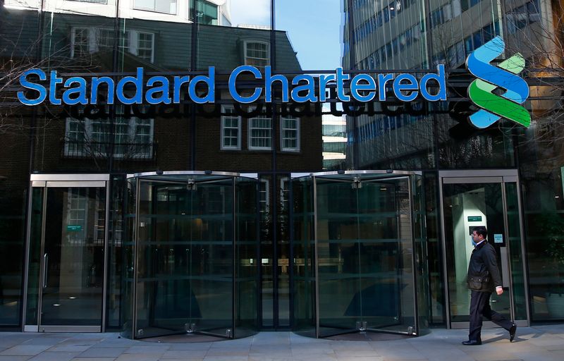 &copy; Reuters. FILE PHOTO: A man walks past the head office of Standard Chartered bank in the City of London