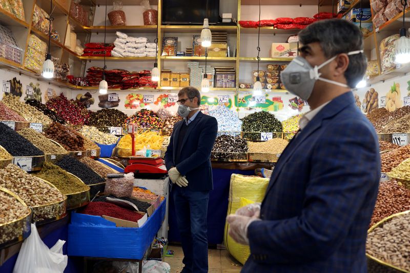 &copy; Reuters. FILE PHOTO: Men wear protective face masks and gloves, following the outbreak of coronavirus, as they are seen in a nuts shop in Tehran