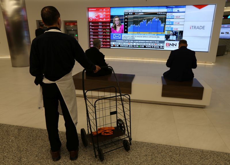 &copy; Reuters. Passersby watch the performance of stocks on a financial news television screen in the business district of Toronto