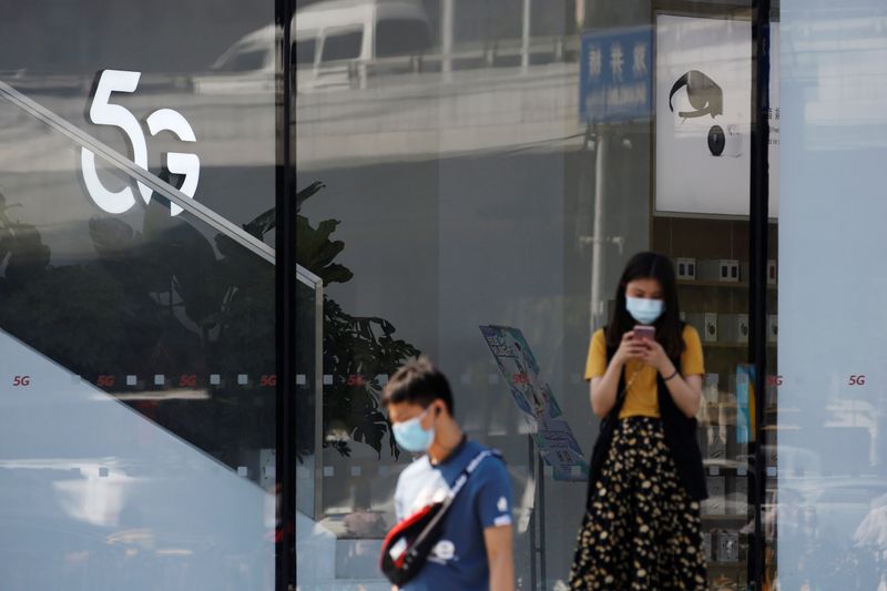 © Reuters. Woman uses a mobile phone outside a Huawei store with a 5G sign in Beijing