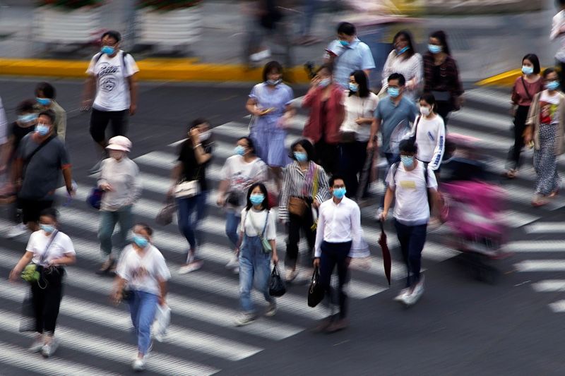 &copy; Reuters. People wearing face masks walk on a street in Shanghai