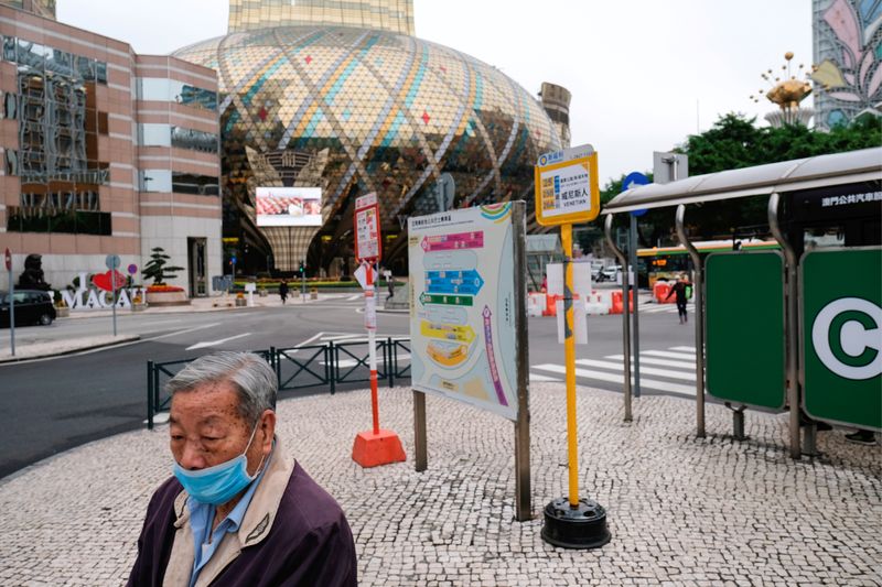 © Reuters. FILE PHOTO: A man wears a mask as he walks in front of the closed Grand Lisboa casino in Macau
