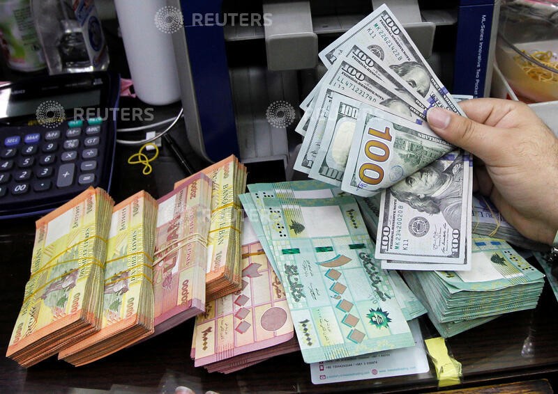 © Reuters. A man counts U.S. dollar banknotes next to Lebanese pounds at a currency exchange shop in Beirut