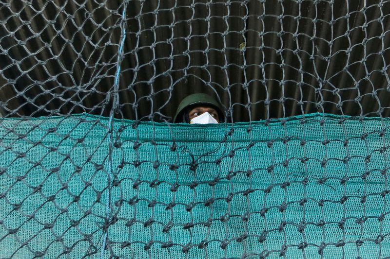 &copy; Reuters. An Indian Central Reserve Police Force (CRPF) officer stands guard at a post during curfew ahead of the first anniversary of the revocation of Kashmir&apos;s autonomy, in Srinagar