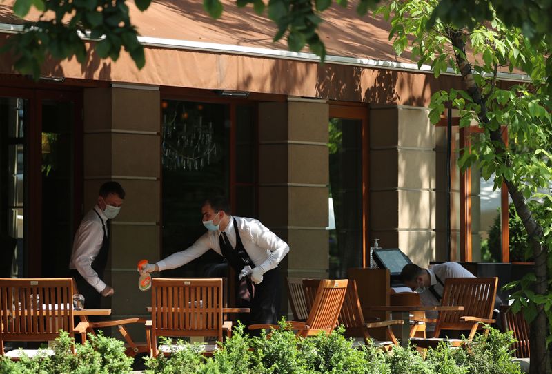 &copy; Reuters. Официанты в защитных масках в московском кафе