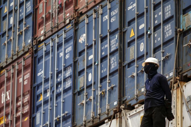 &copy; Reuters. FILE PHOTO: A worker stands next to shipping containers on a ship at a port in Bangkok