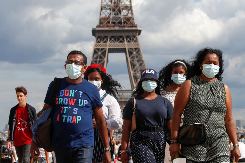 &copy; Reuters. Pessoas com máscaras de proteção perto da Torre Eiffel, em Paris