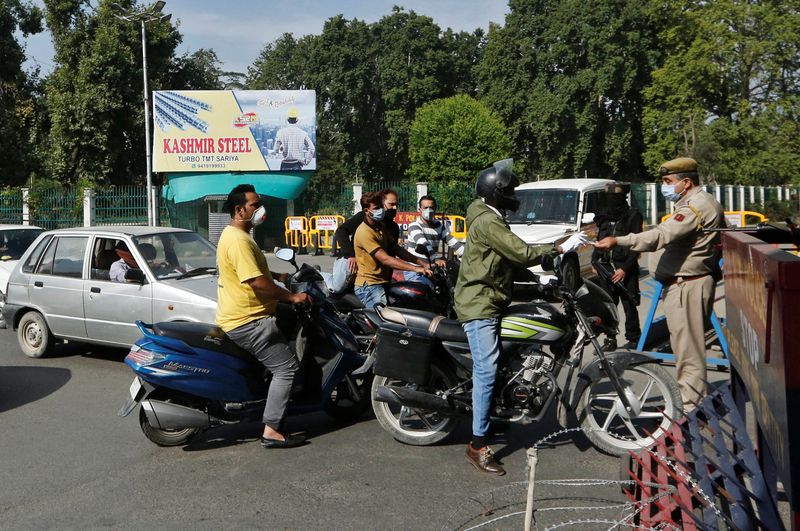 &copy; Reuters. Indian police officers check identification papers of residents at a security barricade during curfew ahead of the first anniversary of the revocation of Kashmir&apos;s autonomy, in Srinagar