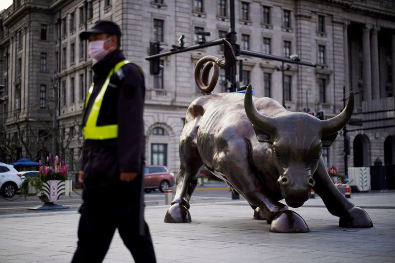 &copy; Reuters. FILE PHOTO: Security guard wearing a face mask walks past the Bund Financial Bull statue on The Bund in Shanghai